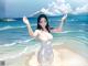 A woman in a white bathing suit standing on a beach.