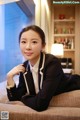 A woman in a business suit sitting on a couch.