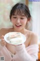 A woman holding a plate with a piece of cake on it.