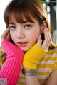 A young woman wearing a yellow and white striped shirt and pink gloves.