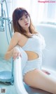 A woman sitting in a bathtub in a white dress.