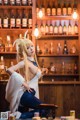 A woman sitting on a stool in front of a bar.