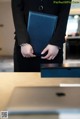 A woman in a business suit holding a blue folder.