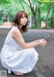 A woman in a white dress sitting on the ground.