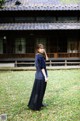 A woman standing in front of a building in a field.