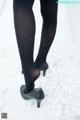 A close up of a woman's legs in black tights and high heels.