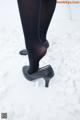 A close up of a woman's legs in black tights and high heels.