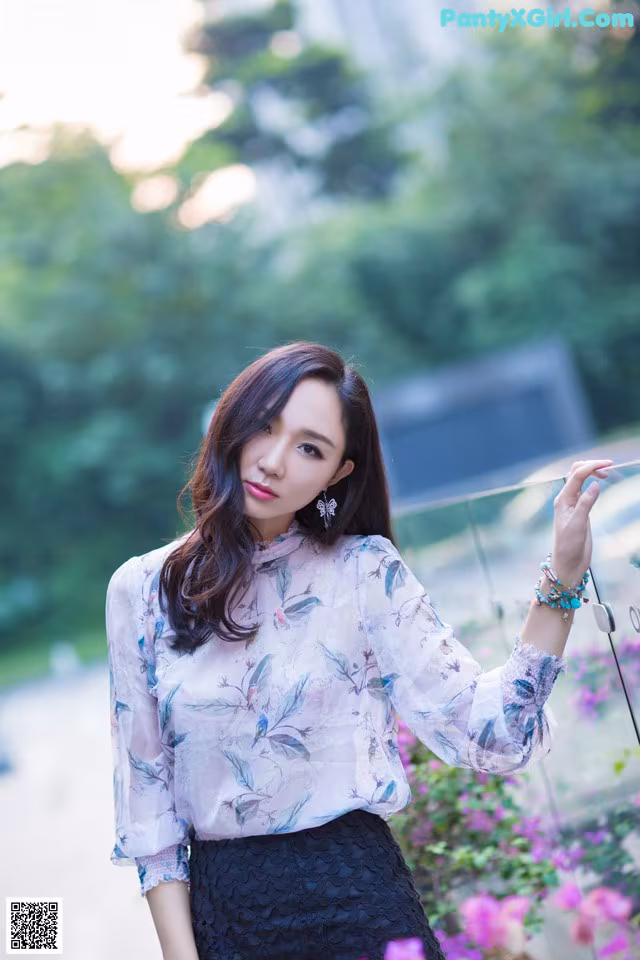A woman in a white blouse and black skirt posing for a picture.