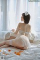 A woman sitting on a bed in a white lingerie.