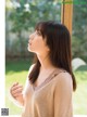 A woman standing in front of a window looking out the window.