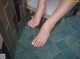 A woman's feet in a bathtub with water on the floor.