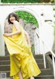 A woman in a yellow dress standing on some steps.