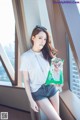 A woman sitting on a window sill holding a bag of chips.