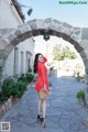 A woman in a red polka dot dress is standing in an archway.