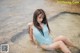 A woman in a blue bathing suit sitting in the water.