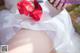 A woman in a wedding dress holding a bouquet of red roses.