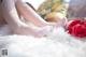 A woman laying on a bed with a bouquet of roses.