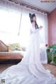 A woman in a wedding dress standing in front of a window.