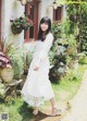 A woman in a white dress standing in front of a house.