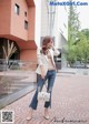 A woman in a white blazer and jeans talking on a cell phone.