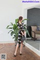 A woman in a black and white dress standing in front of a plant.