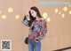 a woman standing in front of a wall wearing a floral blouse