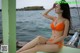 A woman in an orange bikini sitting on a boat.