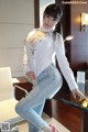 A woman in a white shirt and jeans posing for a picture.