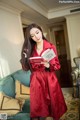 A woman in a red robe holding a book.