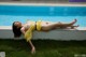 A naked woman laying on the edge of a swimming pool.