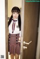 A woman in a school uniform standing in front of a door.