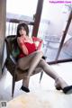 A woman in a red dress sitting on a chair.