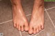 A woman's feet covered in soap on a tiled floor.