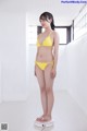 A woman in a yellow bikini standing on a scale.