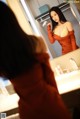 A woman in a red dress looking at herself in the mirror.