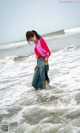 A woman standing in the ocean with her back to the camera.