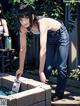 A woman in jeans and a tank top is washing her hands.