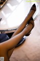 A woman's legs in high heels sitting on a table.