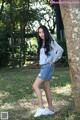 A woman standing next to a tree in a park.