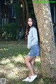 A young woman leaning against a tree in a park.