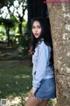 A woman leaning against a tree in a park.