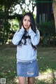 A woman in a gray sweatshirt and a denim skirt posing for a picture.