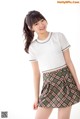 A woman in a white shirt and plaid skirt posing for a picture.