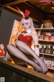 A woman in a bunny costume sitting on a bar.