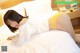 A woman laying on a bed in a white shirt and yellow panties.