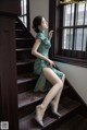 A woman in a green dress sitting on a set of stairs.