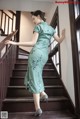 A woman in a green dress is walking up some stairs.