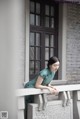 A woman in a green dress leaning on a railing.