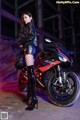 A woman standing next to a motorcycle in a dark room.