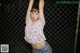 A woman standing in front of a chain link fence.